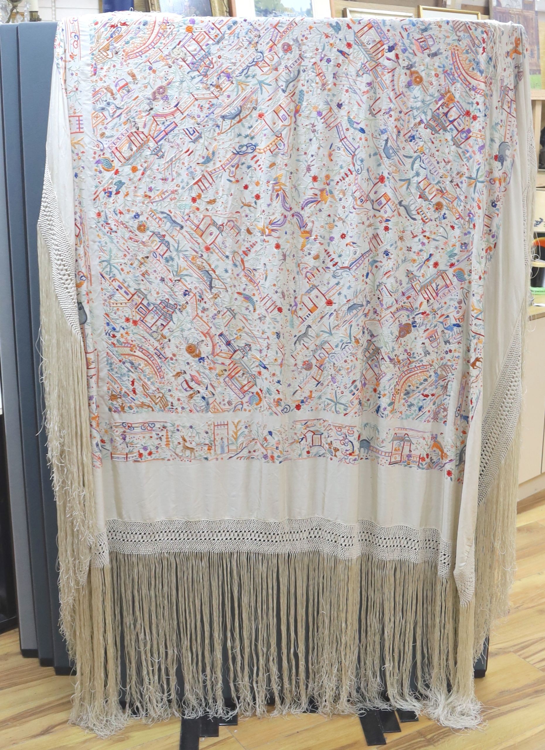 A Chinese cream silk shawl with fine multi coloured all over embroidery depicting figurative scenes and animals